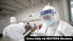 在武漢一家醫院，一名身著防護服的醫護人員在查看病人的病歷。（2020年2月13日）。