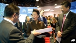 2015年10月21日，中国国家主席习近平夫妇访问伦敦帝国理工学院期间，中国第一夫人彭丽媛在接受赠送的礼物。（美联社照片）