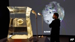 一位参观者正在中国国家博物馆观看嫦娥5号探月火箭2021年3月12号从月球采集到的新岩石样本。中国宣布他们在月球岩石中发现了一种新物质，取名叫“嫦娥石”。（美联社照片）