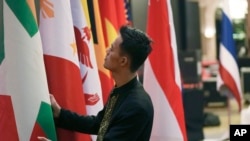 东盟国家联盟（ASEAN）十国外长和中国官员2023年7月10号在印度尼西亚首都雅加达举行避免在南中国海地区发生重大武装冲突会议。一位印尼工作人员正在整理国旗。