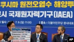 2023年7月9日，在南韓首爾舉行的一次會議上，議員禹元植展示了福島污染水的擬議處理方法，議員魏聖坤和國際原子能機構總幹事拉斐爾·格羅西（右）在一旁觀看。