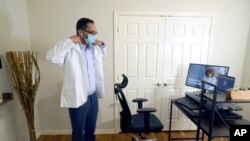 FILE - Medical director of Doctor on Demand Dr. Vibin Roy prepares to conduct an online visit with a patient from his work station at home, April 23, 2021, in Keller, Texas. 