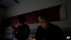 资料照片：中国律师王全璋与妻子李文足在黑暗中查看手机，他们在北京的住所电力被当局切断（2023年6月20日）