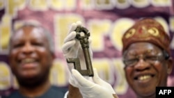 A Benin bronze artifact — one of the thousands of plaques, sculptures and objects looted from the ancient Kingdom of Benin — is held up in Abuja, Nigeria, on Dec. 20, 2022, the same day Germany handed back several looted artifacts to Nigeria.