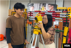 正在与同学操作经纬仪的明新科技大学土木工程与环境资源管理系三年级印尼籍学生马欣怡(Happy Mareta) (右) (美国之音/林柏宏)