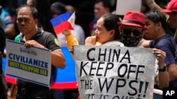 菲律賓漁民和活動人士在中國駐馬卡蒂領事館前舉牌抗議中國海警執法新規。（2024年6月11日）