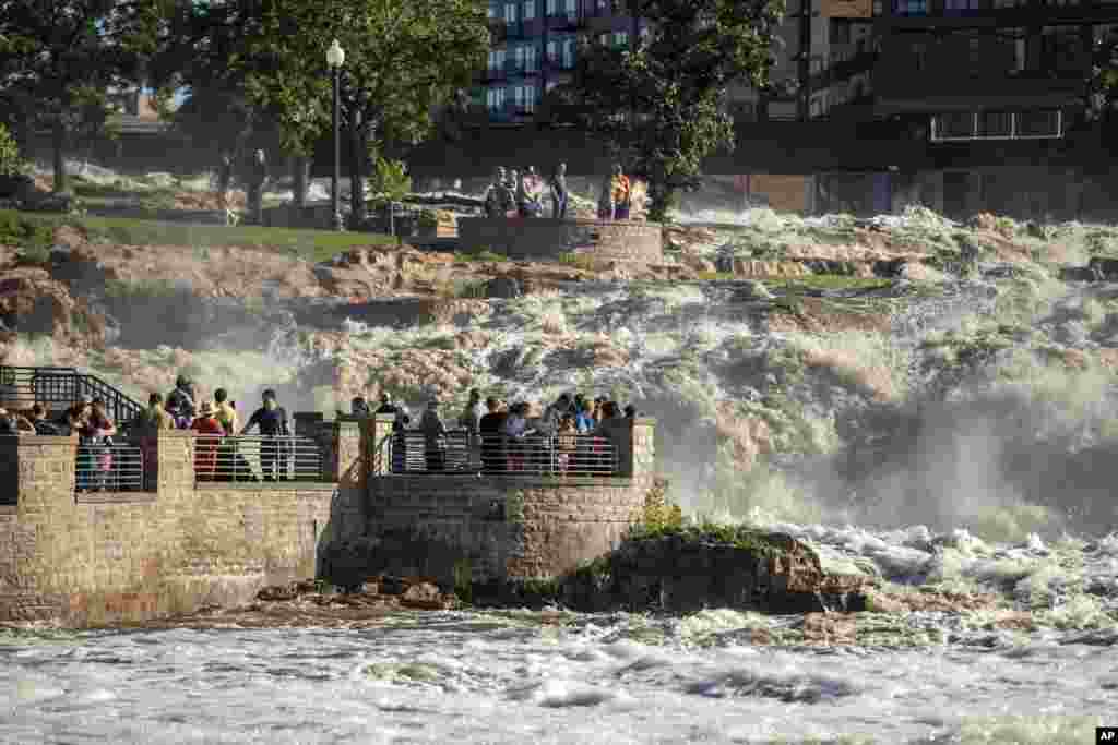 Many families embark on Falls Park in Sioux Falls, Southy Dakota, as water rose quickly, June 22, 2024, after days of heavy rain led to flooding in the area.