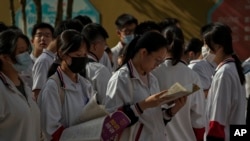 北京的中学生在进入高考考场前温习功课。（美联社2023年6月7日）