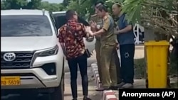 在这张由一位不愿透露姓名的消息人士拍摄的影片中，两名活动人士中的一位（左）与中国维权律师卢思位（右）同行，与拘留卢思位的警察发生争执，2023 年7月28 日 （匿名消息来源向美联社提供照片）