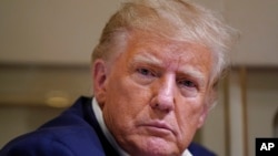 资料照片: 2023年3月25日，在德克萨斯州韦科的韦科地区机场举行的竞选集会后，前总统唐纳德·特朗普在飞机上与记者交谈时在倾听。