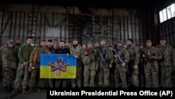 烏克蘭總統澤連斯基（中）前往俄烏正在激戰的巴赫穆特附近的一處陣地與烏軍士兵舉著軍旗合影。（2023年3月22日）