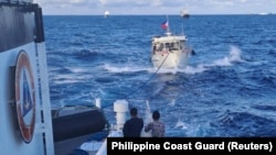 一艘菲律賓'海岸警衛隊船隻拖著一艘遭中國海岸警衛隊水砲攻擊毀壞了的菲律賓供應船駛向有爭議的第二托馬斯島礁（中國稱為仁愛礁）。（2023年12月10日）