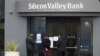 FILE - People look at signs posted outside an entrance to Silicon Valley Bank in Santa Clara, California, March 10, 2023. 