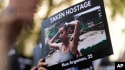 在倫敦的英國首相官邸唐寧街10號外舉行支持以色列的集會上，一人手舉一名25歲的以色列姑娘被巴勒斯坦武裝份子劫為人質的照片。（2023年10月9日）