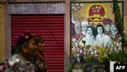 兩名維吾爾婦女從喀什街道樹立的政府宣傳畫前走過。 （2023年7月14日）