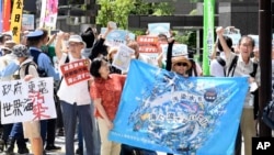 2023年8月24日，在東京電力公司控股公司（TEPCO）總部前，一名抗議者在集會上舉著標語牌，反對受損的福島核電站排放經過處理的放射性水。