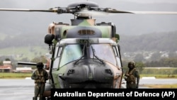 澳大利亚皇家海军飞行员站在一架MRH90太攀蛇（Taipan）直升机旁。（2021年11月27日）