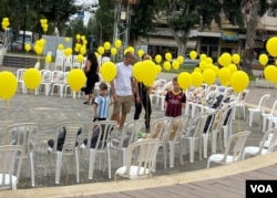 特拉维夫北边的拉马特哈沙隆（Ramat Hasharon）的市政府大楼旁的圆环广场有市民自发设置、摆放近200多张白色空椅、各张椅子上贴有被绑人质照片的小海报、幼童人质的椅子上还置放了泰迪熊等毛绒玩具，表达人们对人质及人质家人的支持和关注。(美国之音/赖素芬)