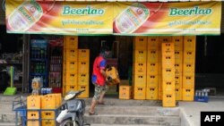 ຊາຍຄົນນຶ່ງກຳລັງຂົນລັງເບຍໄປສົ່ງຮ້ານຄ້າແຫ່ງນຶ່ງໃນຫຼວງພະບາງ ເມື່ອວັນທີ 27 ມັງກອນ 2024. (Photo by TANG CHHIN SOTHY / AFP)