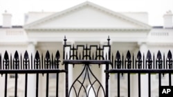 ແຟ້ມພາບ - ທຳນຽບຂາວ ແມ່ນເຫັນໄດ້ຜ່ານຮົ້ວເຫຼັກ ຢູ່ເດີ່ນຫຍ້າກ້ຳເໜືອ ໃນນະຄອນຫຼວງວໍຊິງຕັນ, ເມື່ອວັນທີ 16 ພຶດສະພາ 2016. 