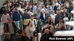 Travelers walk through Salt Lake City International Airport, May 24, 2024, in Salt Lake City. A record number of Americans are expected to travel over the 2024 Memorial Day holiday.