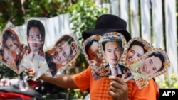 ຄົນ​ຂາຍ​ເຄື່ອງ​ຜູ້​ນຶ່ງ ພວມ​ຍົກ​ຮູບ​ ຜູ້​ນຳ​ພັກ​ກ້າວ​ໄກ ແລະ​ຜູ້​ທີ່​ກຳ​ລັງ​ສະ​ໝັກ​ເອົາ​ຕຳ​ແໜ່ງ​ນາ​ຍົກ​ລັດ​ຖະ​ມົນ​ຕີ​ຂອງ​ໄທ ທ່ານ​ພິ​ທາ ລິ້ມ​ຈະ​ເຣີນ​ຣັດ ທີ່​ບາງ​ກາງ ເມື່ອ​ວັນ​ທີ 12 ພຶດ​ສະ​ພາ 2023.