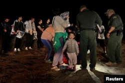 一名兩歲的中國幼童跟隨他的家人渡過美墨邊境的格蘭德河進入美國德克薩斯州，這家人正在美國邊境巡邏人員那裡登記以便進入移民程序。（2023年3月23日）