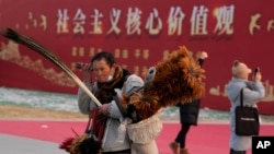 北京一名街頭小販走過「社會主義核心價值」的宣傳牌。 （2024年1月20日）