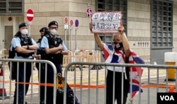 香港社运人士王婆婆2月13日连续多日到西九龙裁判法院外示威，声援民主派初选47人案各被告，她高举“立即释放所有政治犯”的标语 (美国之音/汤惠芸)