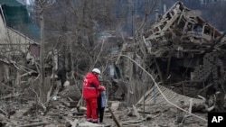 ພະນັກງານການແພດຄົນນຶ່ງ ປອບໃຈແມ່ຍິງຄົນ ຢູ່ທີ່ບໍລິເວນທີ່ເກີດເຫດການໂຈມຕີທາງອາກາດຈາກຣັດເຊຍ, ໃນເມືອງຊາໂປຣິສເຊຍ, ປະເທດຢູເຄຣນ, ວັນທີ 22 ມີນາ 2024.