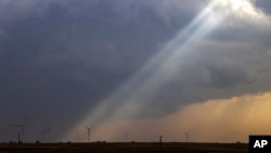 Sunlight filters through storm clouds onto a wind turbine as severe weather rolls through the midwest on Apr. 4, 2023, south of Stuart, Iowa.