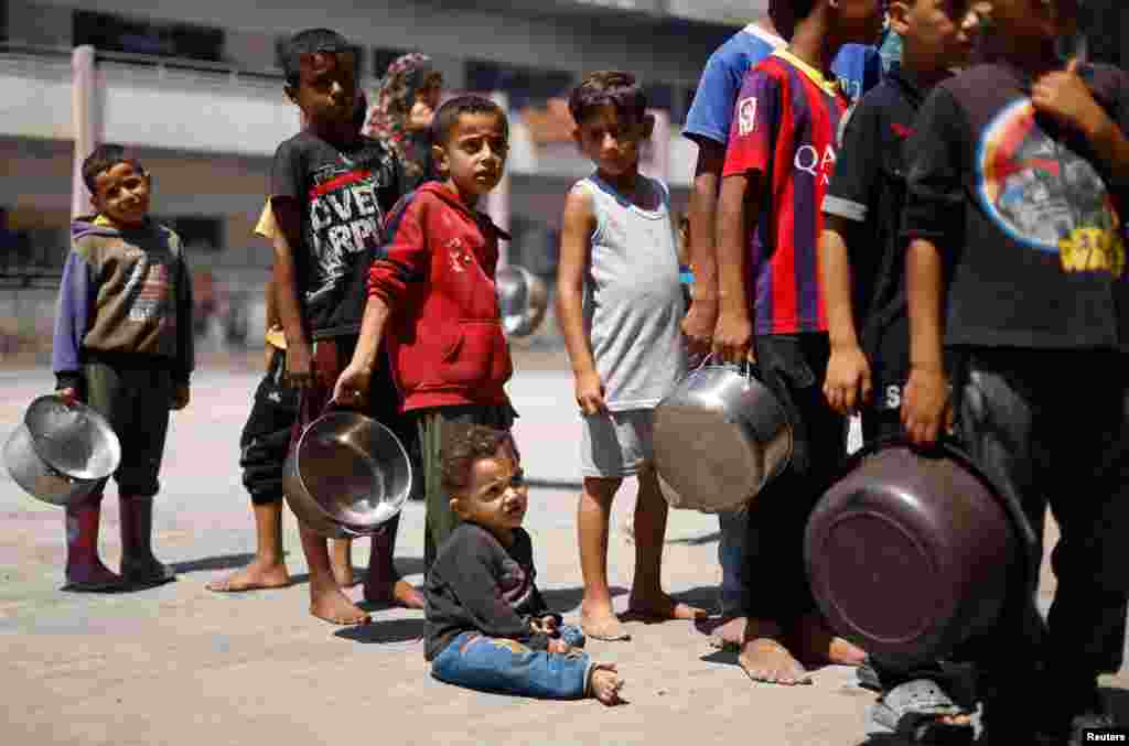Palestinian children gather to receive food cooked by a charity kitchen, amid food scarcity, as Israel-Hamas conflict continues, in Khan Younis in the southern Gaza Strip.