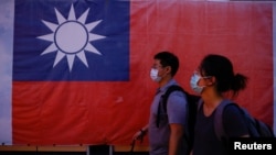 台北街頭民眾走過豎立的台灣旗幟。（2023年8月18日）