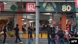 2023 年 4 月 14 日，在印度尼西亞主要島嶼爪哇島以北的海域發生 7.0 級地震後，一家百貨公司的員工在度假勝地巴厘島登巴薩的大樓外等候。