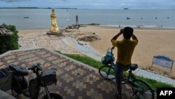 资料照：一名男子在中国厦门用一副望远镜隔海遥望台湾金门岛。（2022年8月3日）