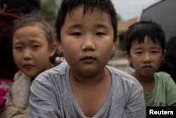 幾名來自中國的兒童和他們的家人渡過美墨邊境的格蘭德河走出美國德克薩斯州的叢林，他們為了進入美國移民程序找到了美國執法人員。（2023年4月5日）