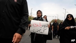 2024年8月25日，在紀念先知穆罕默德的孫子伊瑪目·侯賽因在公元680年被殺後40天哀悼期結束的儀式上，一名哀悼者舉著一塊標語牌，上面寫著：“加沙浸泡在兒童的鮮血中」。 (美聯社照片)