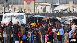 被驱离的巴勒斯坦人在加沙拉法城一个临时营帐前排队购水。（2024年5月17日）