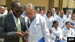 资料照片：肯尼亚基苏木省省长安扬·尼永戈教授（左）与参加位于内罗毕肯尼亚政府学院项目的100名古巴医生之一交谈。（2018年6月11日）