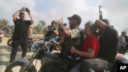 2023年10月7日，一名被俘的以色列平民（中，穿紅衣的女士）被從卡法阿扎基布茲運送到加沙地帶。(AP Photo/Hatem Ali)