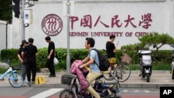 北京街頭大衆經過中國人民大學校園外牆的標誌。 （2024年7月22日）