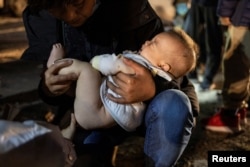 一位来自中国的爷爷抱着三个月大的孙子穿越美墨边界进入德州。（2023年4月1日）