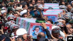 2024年5月23日，在伊朗馬什哈德市舉行的葬禮上，大眾抬著覆蓋著國旗的萊希總統及其同機人員的靈柩。（美聯社照片）