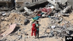 2024年6月21日，以色列轟炸汗尤尼斯後，一名巴勒斯坦兒童手拿從被摧毀建築物的廢墟中找回的毛絨熊。 (法新社照片)