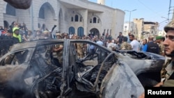 據兩名巴勒斯坦消息人士稱，2024年8月21日的黎巴嫩，在以色列襲擊南部港口城市西頓郊區後，人們和黎巴嫩軍人站在一輛被燒燬的汽車附近。(路透社照片)