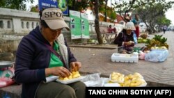 ​ແມ່​ຍິງ​ຄົນ​ນຶ່ງ​ຫໍ່​ໝາກ​ມີ້​ເພື່ອ​ຂາຍ​ຢູ່​ຕາມ​ຖະ​ໜົນ​ໃນ​ນະ​ຄອນຫຼວງ​ພະ​ບາງ, 31 ມັງ​ກອນ 2024.