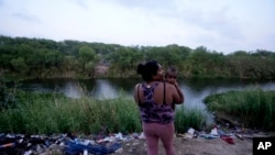 ຜູ້ຍົກຍ້າຍຖິ່ນຖານຈາກຮອນດູຣາສ ນາງມາເຣຍ ຄາຣີນາ ບາລລາດາເຣສ ອຸ້ມລູກຊາຍຂອງລາວ ຢູ່ທີ່ແຄມຝັ່ງແມ່ນ້ຳຣີໂອ ກຣານເດ ຟາກຂອງເມັກຊິໂກ ບ່ອນທີ່ພວກຍົກຍ້າຍຖິ່ນຖານຄົນອື່ນໆ ໄດ້ພາກັນຂ້າມເຂົ້າໄປໃນສະຫະລັດ ເພື່ອມອບໂຕແກ່ ເຈົ້າໜ້າທີ່ກວດຄົນເຂົ້າເມືອງ, ໃນເມືອງມາຕາໂມໂຣສ ຂອງເມັກຊິໂກ, ວັນທີ 11 ພຶດສະພາ 2023.