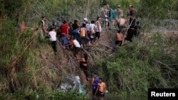 大批來自中美洲的移民渡過美墨邊境的格蘭德河進入美國德克薩斯州，向美國邊境巡邏人員報到。（2023年5月10日）