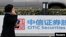 ​ແມ່​ຍິງ​ຄົນ​ນຶ່ງ​ຍ່າງ​ຜ່ານ​ປ້າຍ​ຂອງ​ບໍ​ລິ​ສັດ Citic Securities ຢູ່​ຫ້ອງ​ການ​ໃຫຍ່​ຂອງ​ເຂົາ​ເຈົ້າ​ໃນ​ນະ​ຄອນຫຼວງ ປັກ​ກິ່ງ, ຈີນ, 27 ມີ​ນາ 2013.