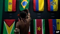 一名土著男子在巴西貝倫舉行的亞馬遜合作會議上觀看巴西國旗。 （2023年8月6日）